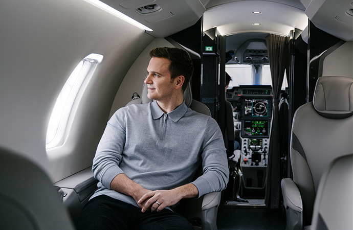 A man looking out the window of a private Air Partner plane